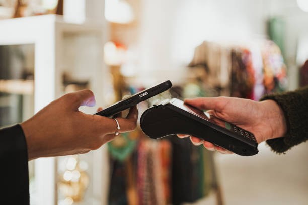 A customer paying by phone at a shop counter card terminal.